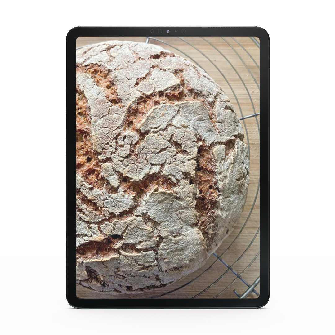 Ein runder Laib rustikalen Brotes aus Ruut Maniokmehl ruht auf einem Kühlregal und ist auf einem Tablet abgebildet - perfekt für glutenfreie Backen-Fans.